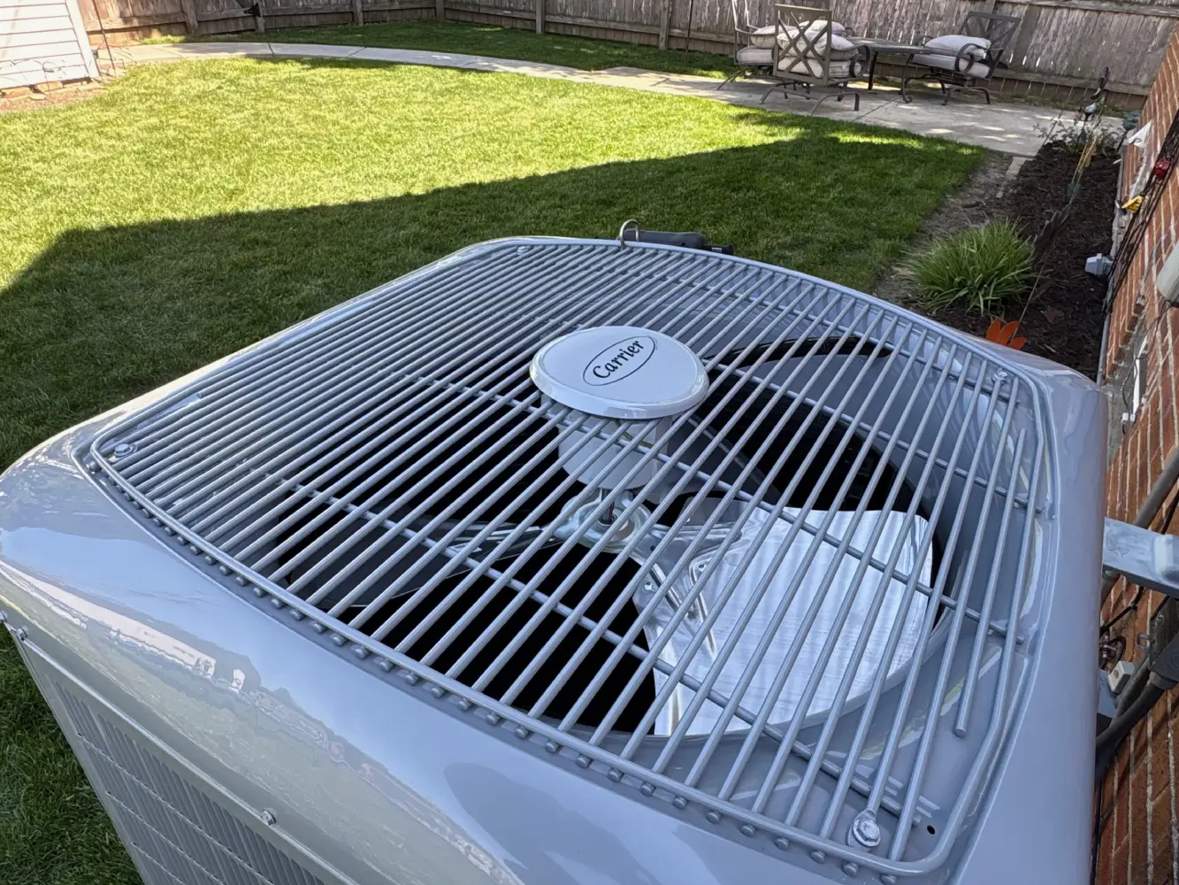 Carrier Heat Pump System Upgrade A newly installed premium Carrier heat pump outdoor condenser unit sitting next to a brick residential home, qualifying for the Wisconsin HEAR program upfront rebates with K Komfort in Milwaukee, Wisconsin.