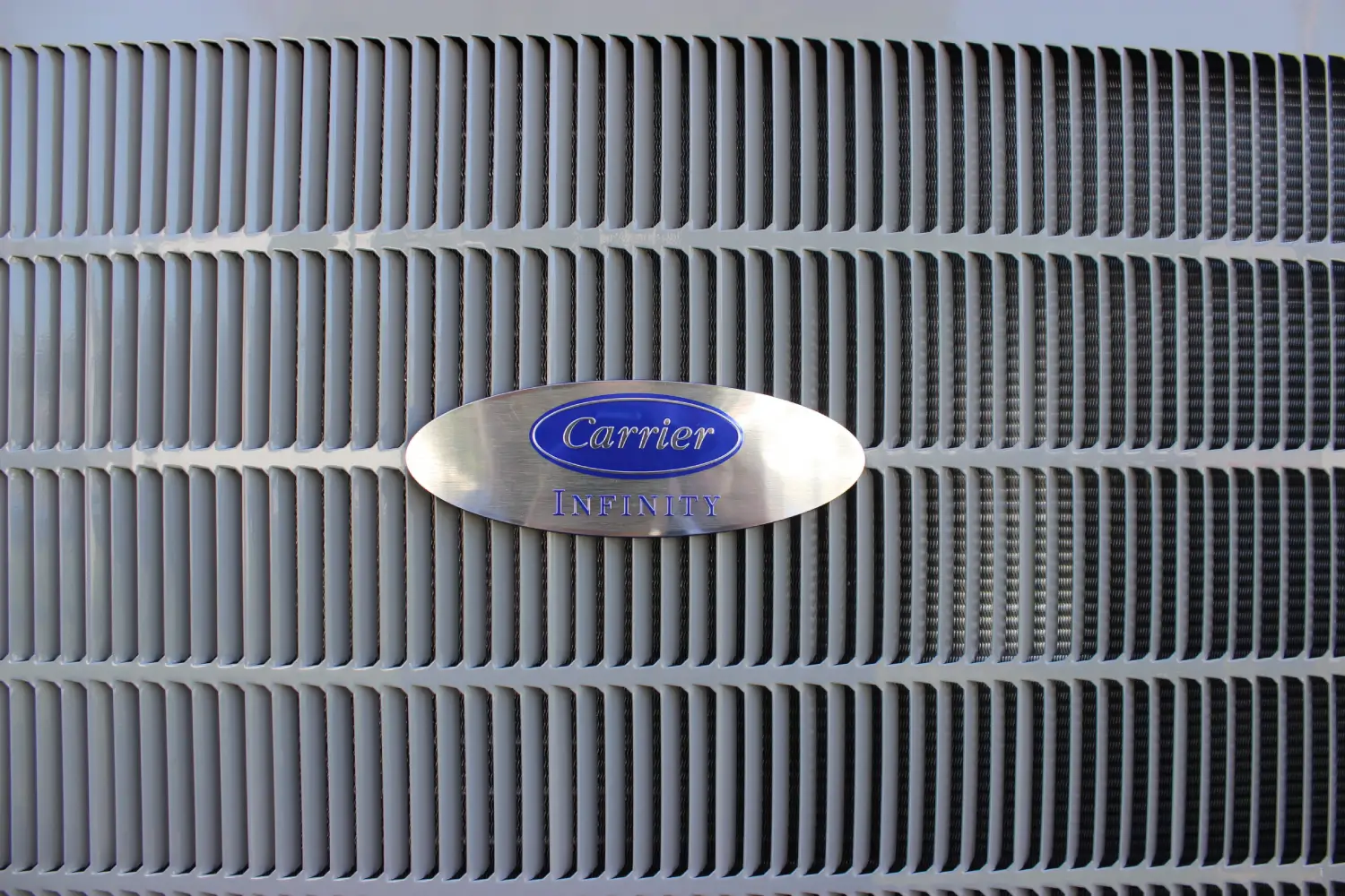 Close-up of a premium Carrier Infinity heat pump condenser grill installed by K Komfort.