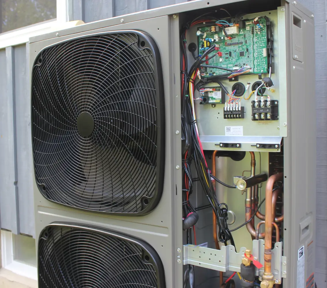 Exposed electrical control board and copper lines of an outdoor heat pump system during an HVAC diagnostic service call by K Komfort.