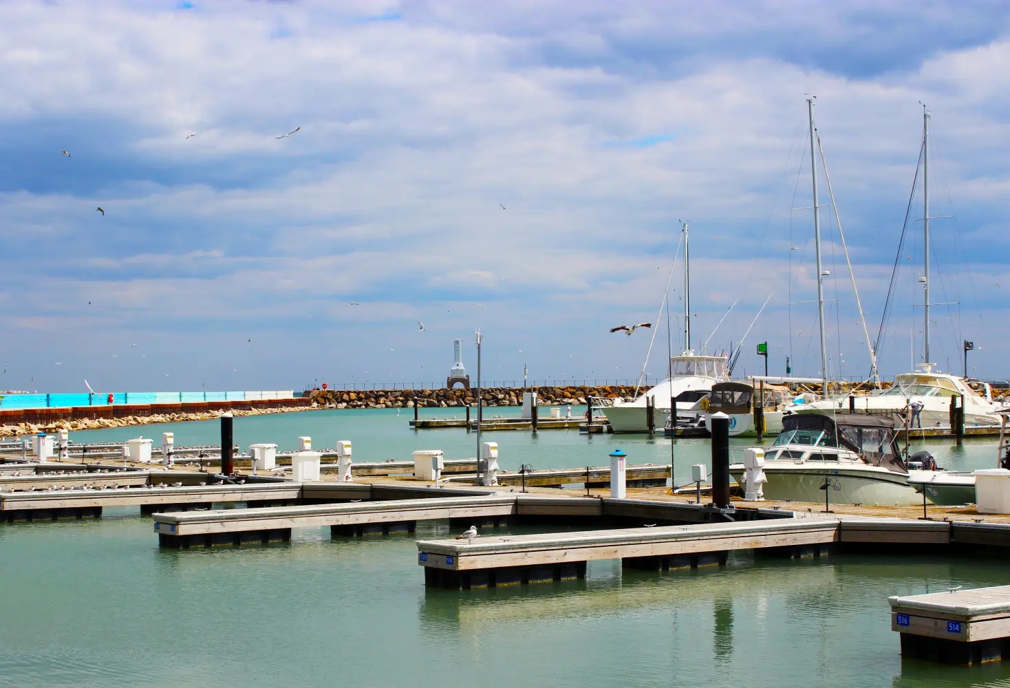 Boats and docks at the Port Washington Marina on Lake Michigan with the historic breakwater lighthouse visible under a cloudy sky in Port Washington, Wisconsin.