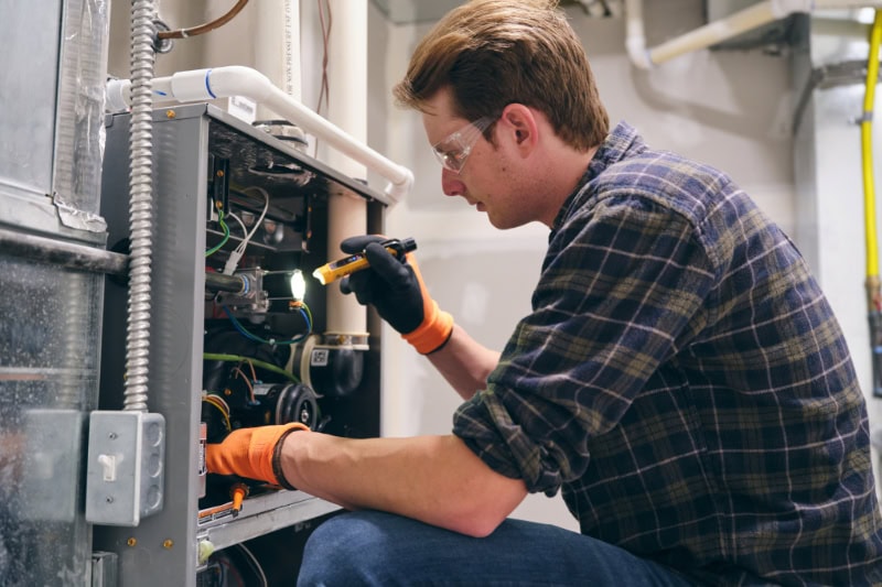What Does AFUE Mean? A repairman working inside a home, repairing a furnace.