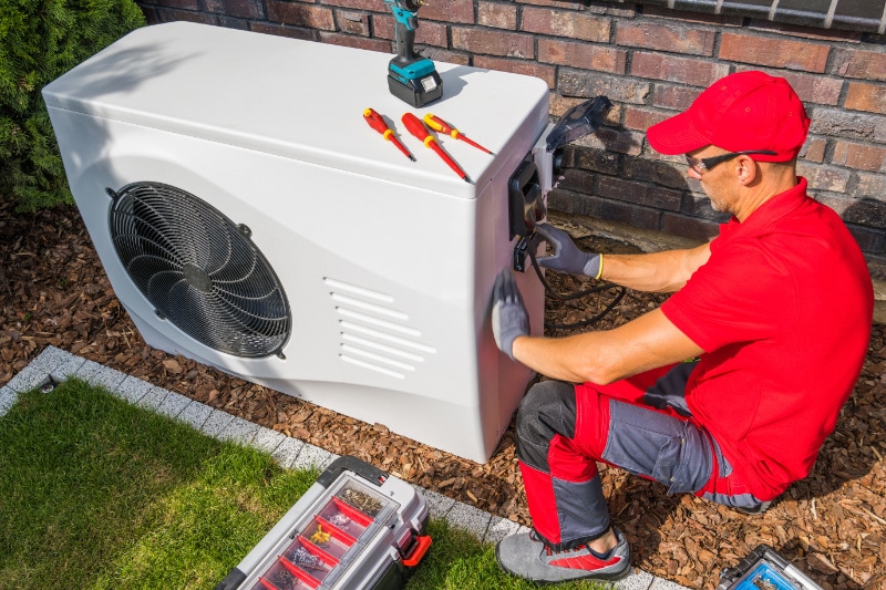 4 Factors to Consider When Buying a Heat Pump. Technician Repairing Heat Pump Unit.