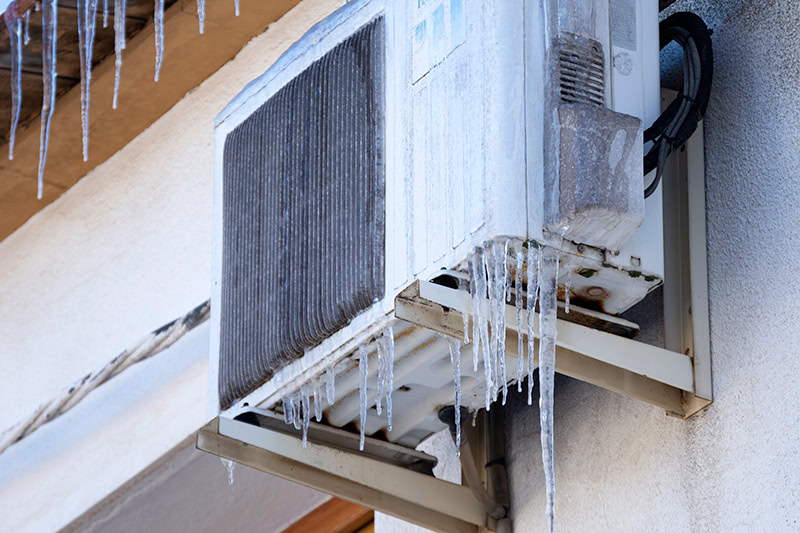A home's heat pump covered in icicles.