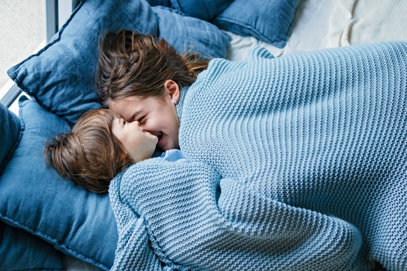 What Is Radon and Why Is It Bad? Two kids cuddling under blue blankets in bed.