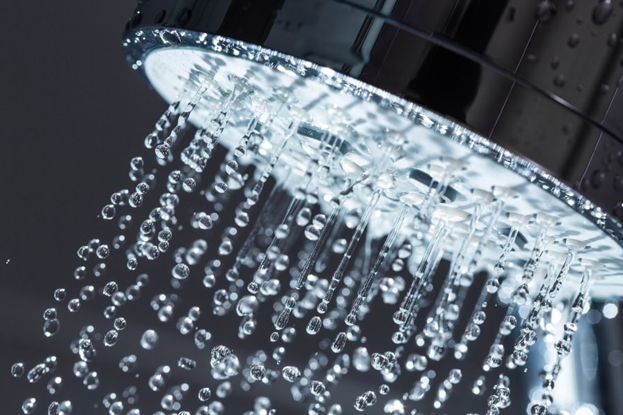 Shower Head with Water Stream on Black Background.