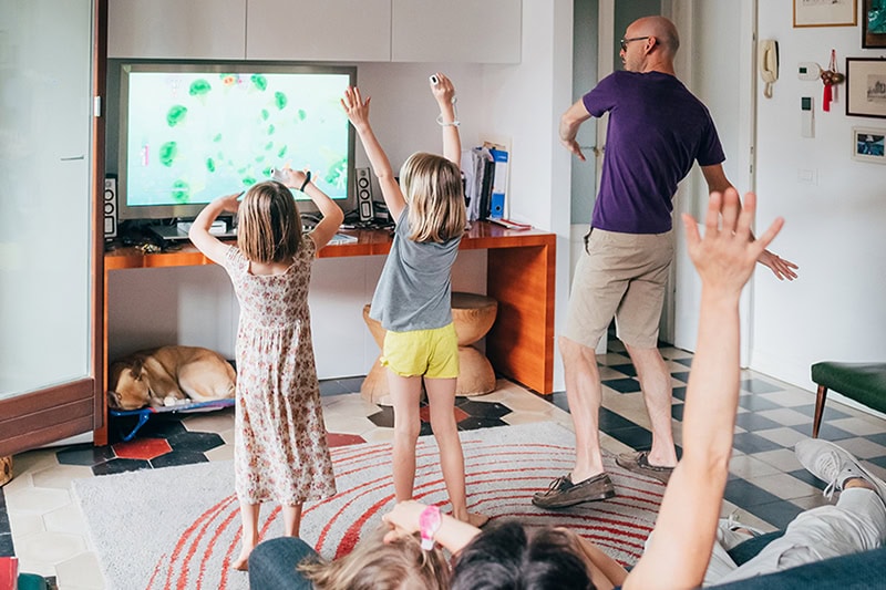 Best Indoor Air Quality (IAQ) Products for Hot Summer Weather. Photo of a father and two children playing a game in their livingroom.